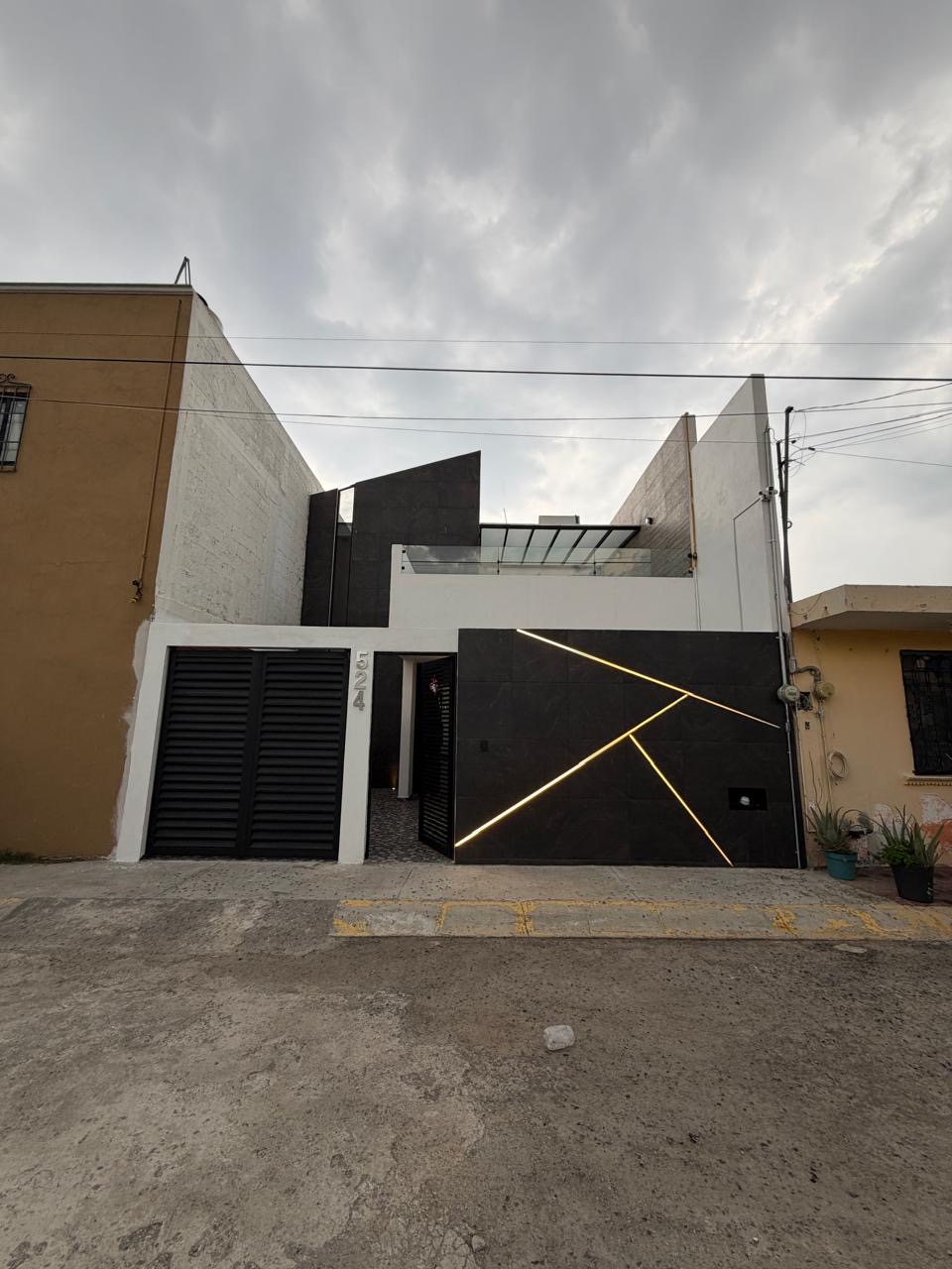 Fachada residencial construida con revestimiento oscuro e iluminación diagonal